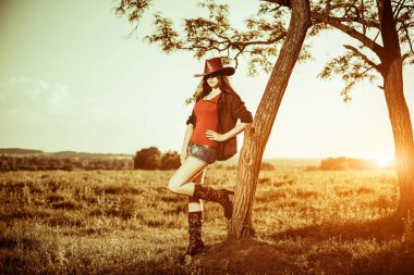 şapka ve kırsal günbatımı manzara ağaca yaslanmış gömlek güzel cowgirl