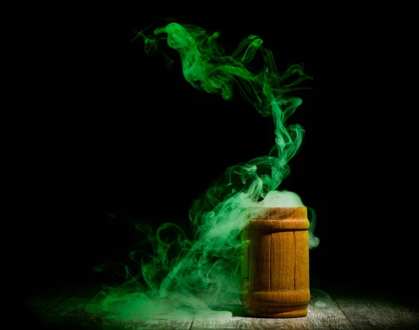 绿色烟雾从木罐隔离在黑暗的背景 — 图库照片