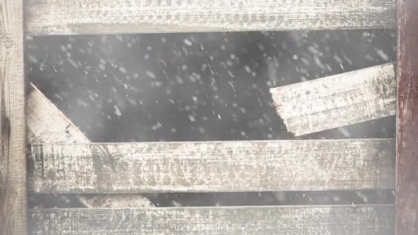 木製フェンスの暗い穴から落ちる雪 — ストック動画