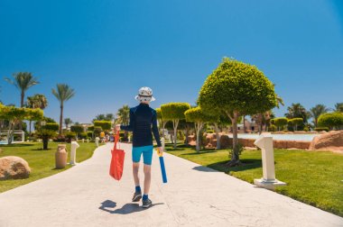 kırmızı çanta ile çocuk denizde yüzmek için dekoratif bahçe ile yürüyüş 