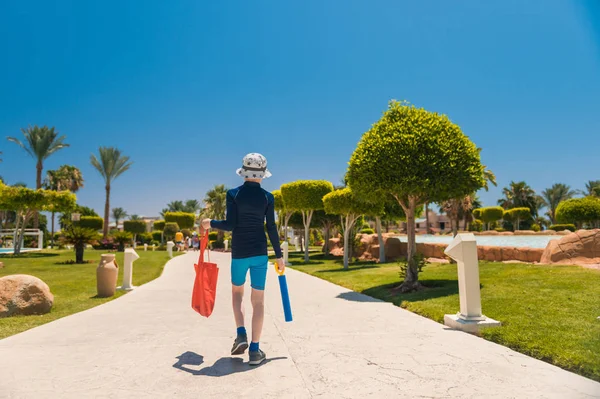 kırmızı çanta ile çocuk denizde yüzmek için dekoratif bahçe ile yürüyüş 