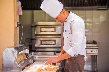 Mısır, Şarm el-Şeyh - 17.06.2019. Bir açık hava kafede turistler için pizza dilimleme mutfakta Mısırlı aşçı