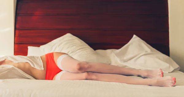 ベッドの上の白いストッキングの若い白人女性の足 — ストック写真