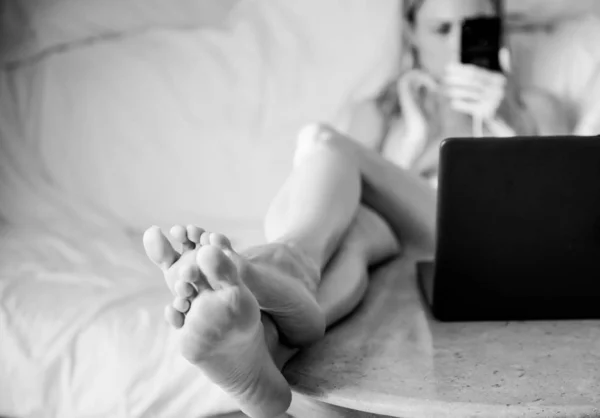 Молода Жінка Сидить Дивані Ногами Над Столом Біля Відкритого Ноутбука — стокове фото