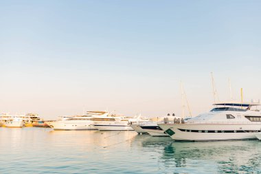 23.07.2020 - Mısır, Hurghada Marina Körfezi limanı park etmiş yatları ve yaz günbatımında deniz üzerinde yelkenli tekneleri