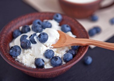 Ekşi krema ve yaban mersini bir kil fincan süzme peynir.