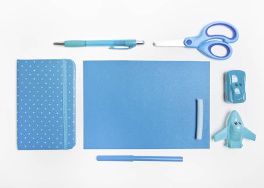 Beyaz arka planda mavi tonlarda oyuncaklar içeren bir dizi kırtasiye eşyası.