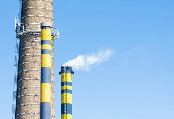 Groep van industriële schoorstenen met rook tegen blauwe hemel — Stockfoto