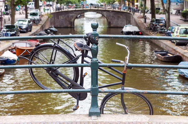 荷兰阿姆斯特丹悬挂在桥栏杆上的旧废弃自行车 — 图库照片
