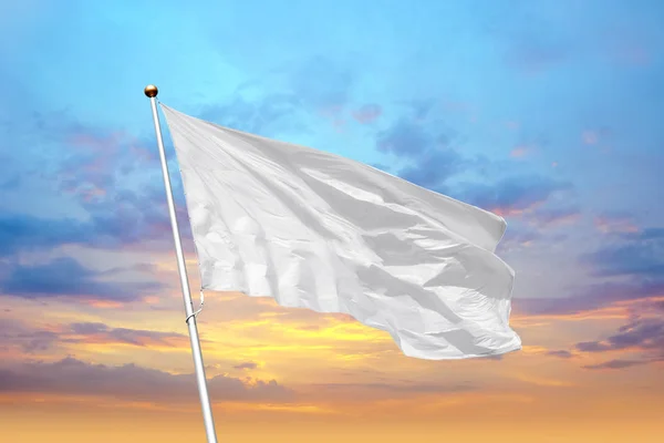 Leere weiße Flagge auf einer Stange, die im Wind vor dem Hintergrund des Sonnenuntergangs weht — Stockfoto