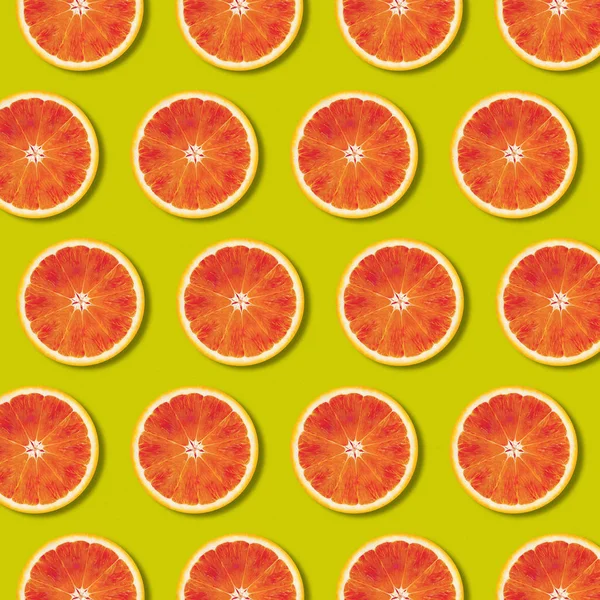 Geometric red orange fruit slices pattern on green color background — Stock Photo, Image
