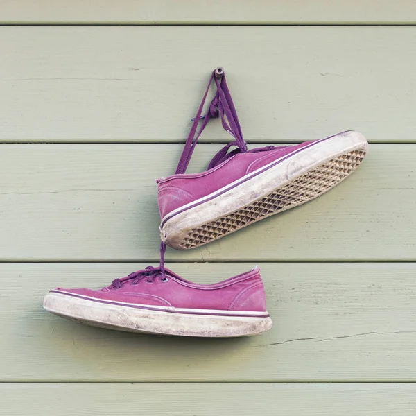 Par de zapatillas wornout viejas rojas colgando en la pared — Foto de Stock