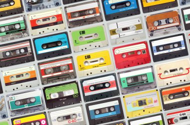 Gri arkaplandaki eski kasetlerden oluşan geniş bir set, renkli retro müzik arka planı.