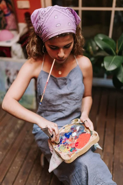 プロ女性アーティストのスタジオで彼女の口にブラシでキャンバスに絵画の室内撮影 — ストック写真