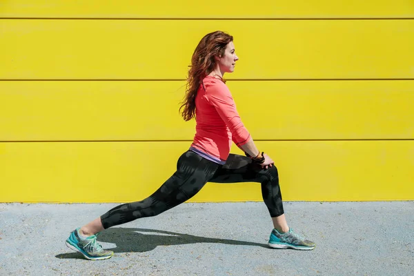 Mujer Joven Estirándose Suelo Frente Una Pared Amarilla Antes Correr — Foto de Stock