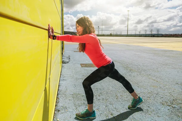 Młoda Kobieta Rozciągający Się Żółtej Ścianie Przed Uruchomieniem — Zdjęcie stockowe