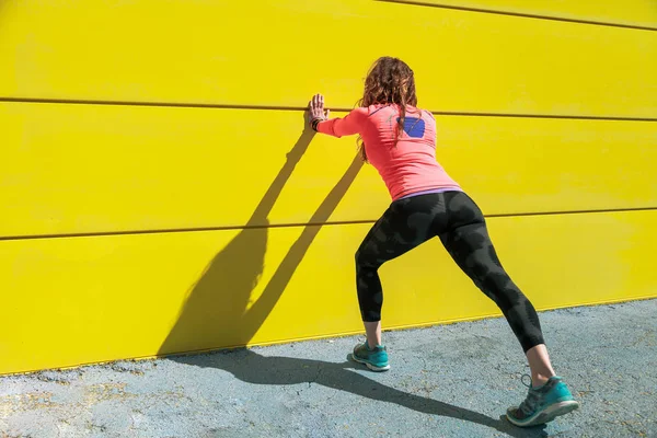 Mujer Joven Estirándose Una Pared Amarilla Antes Correr — Foto de Stock