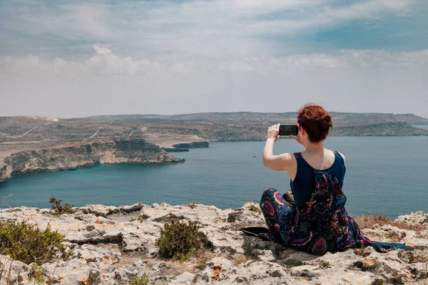 Uçurumun Kenarında Deniz Ile Smartphone Resmini Alarak Oturan Topuz Ile — Stok fotoğraf