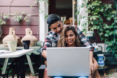İçinde belgili tanımlık merdiven ahşap evlerinin bir dizüstü bilgisayar ile kucakladı oturan genç çift gülümseyen