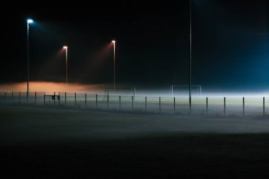 Projektör tarafından aydınlatılmış sadece geceleri tarafından sis kaplı yalnız futbol sahası