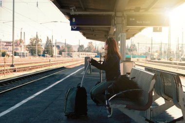 Bir sonraki tren istasyonunda onu çanta ve sırt çantası ile bekleyen genç Kızıl saçlı kadın