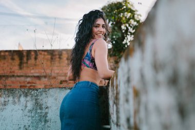 Gülümseyen genç esmer kadın eski boş bir havuza bikini ile