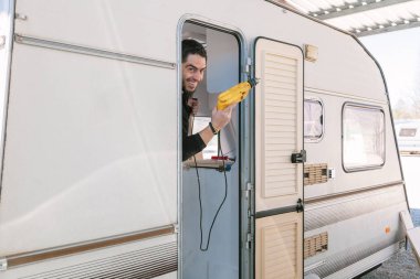 Genç gülümseyen adam onun eski karavan geri yükleme bir matkap ile