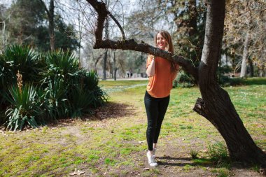 Genç sarışın kadın siyah kot ile bir ağaç üzerinde desteklenen