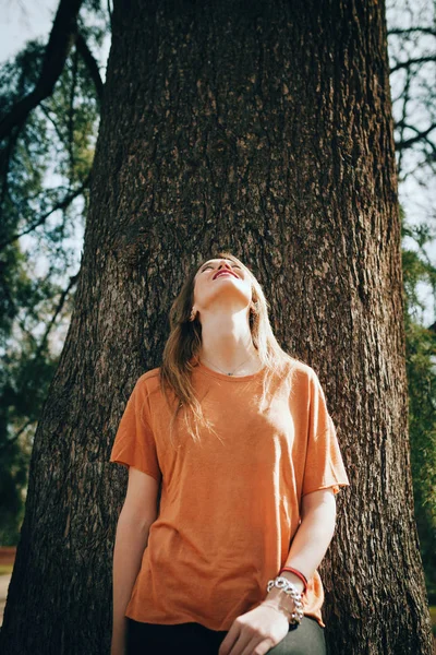 Mladá blond žena podporované na stromě s černé džíny — Stock fotografie