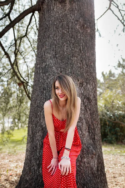 Junge lächelnde Frau mit rotem Kleid lehnt in die Kamera — Stockfoto