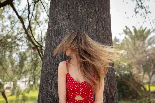 Junge lächelnde blonde Frau mit rotem Kleid, die ihre Haare bewegt — Stockfoto