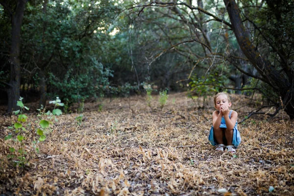 Solitario triste bambina accovacciato in il foresta . — Foto Stock