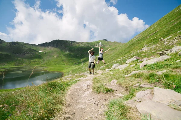 Genç çift bir göl ile büyük bir vadide atlama — Stok fotoğraf