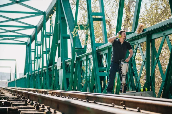Молодий будівельник читає книгу на старому залізничному мосту — стокове фото