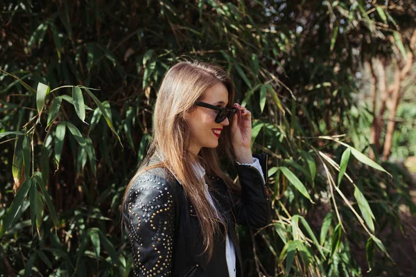 Joven mujer rubia sonriente con una chaqueta de cuero en el parque — Foto de Stock