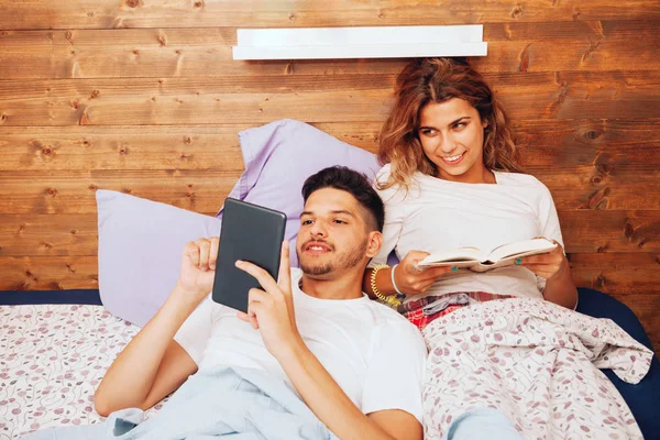 Jeune couple hétérosexuel souriant couché ensemble sur le lit — Photo