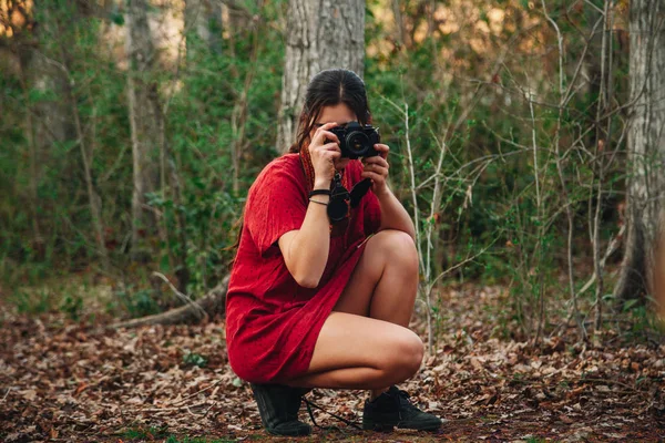 Jonge vrouw maakt foto 's in het bos in een mini jurk. — Stockfoto