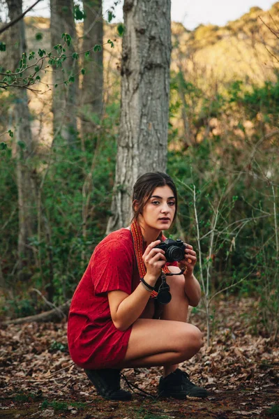 Jovem mulher tirando fotos na floresta usando um mini vestido . — Fotografia de Stock