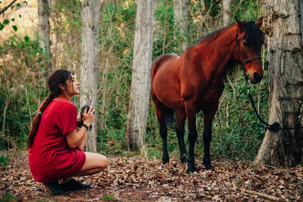 Jeune femme prenant des photos dans la forêt avec son cheval — Photo