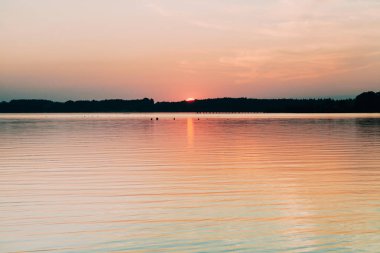 Chiemsee gölünde ufkun arkasına saklanan güneş