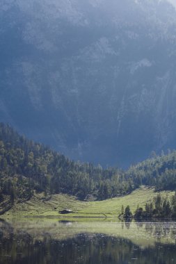 Gün batımında dağların arasında bir Alman gölü yakınında ev.