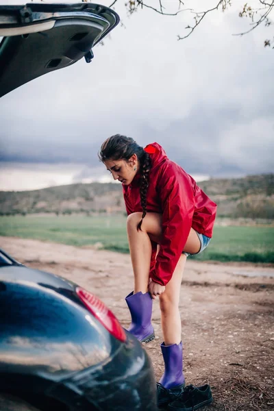 Mädchen stellt ihre wasserdichten Stiefel in die Nähe ihres Autos. — Stockfoto