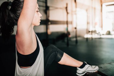 Kettlebell ile ev içi egzersizleri yapan genç bir kadın.