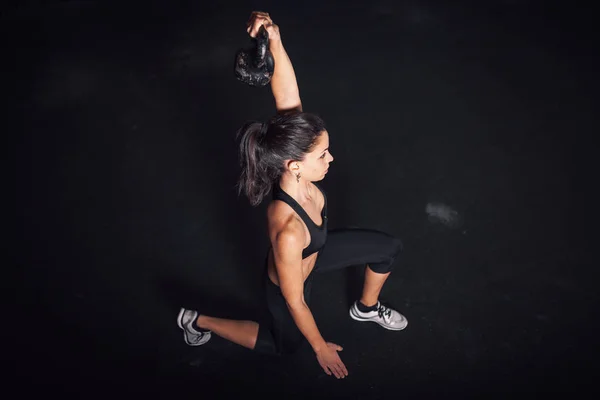 Kettlebell ile ev içi egzersizleri yapan genç bir kadın.