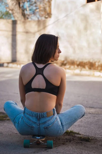 Mujer joven sentada en su patín en una vieja calle industrial —  Fotos de Stock