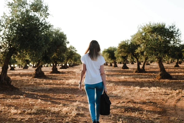 Jonge vrouw met een laptoptas door het veld van de olijfboom — Stockfoto