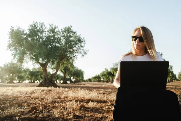 Jovem com um estojo de laptop sentado no campo da oliveira — Fotografia de Stock