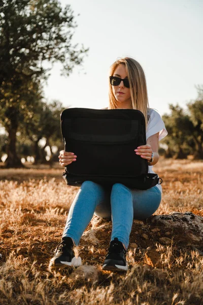 Giovane donna con una custodia per computer portatile seduta nel campo di ulivi — Foto Stock