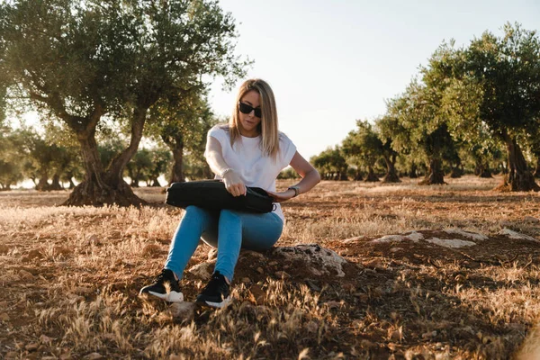 Jeune femme avec un ordinateur portable assis dans le champ d'olivier — Photo