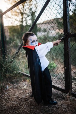 Izgara yakınındaki ormanda cadılar bayramı için dracula kostümlü çocuk